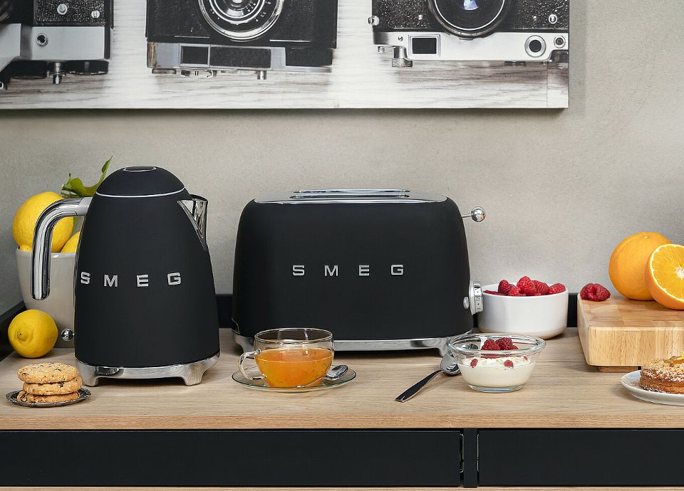 Un toaster et une bouilloire Smeg à la finiton noire mate sur un meuble en bois.