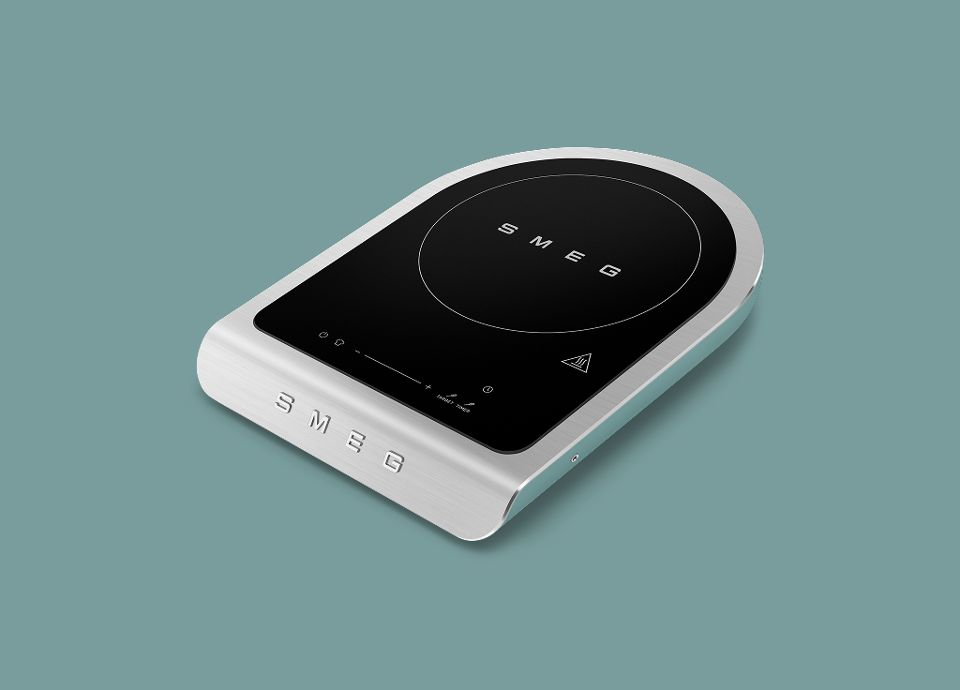 Piano cottura a induzione portatile SMEG con superficie in vetro nero e corpo in acciaio inossidabile.