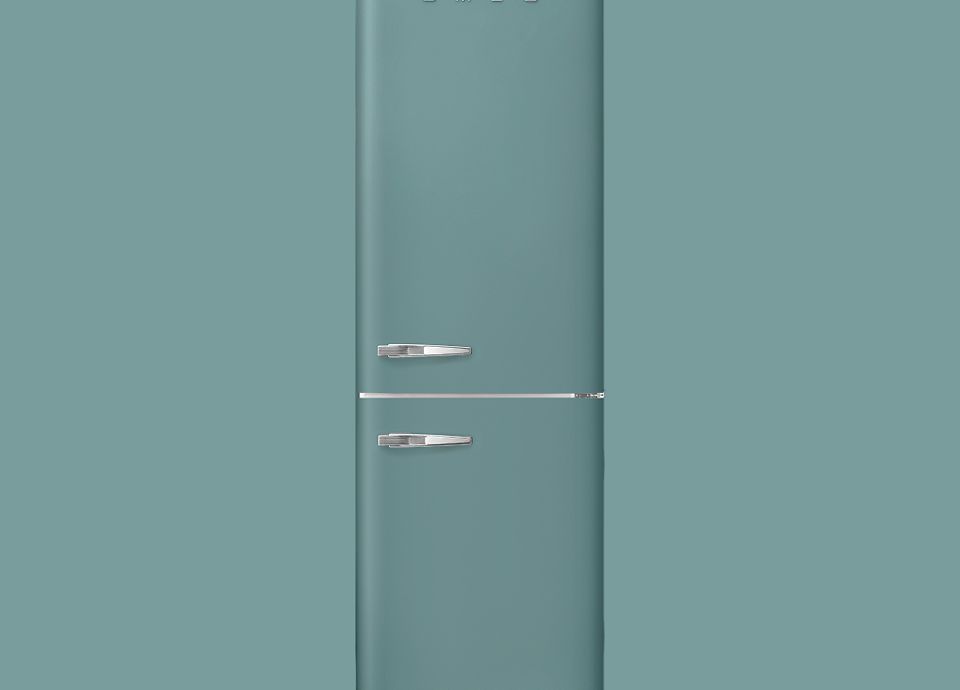 Frigorifero SMEG a tutta altezza in stile retrò con vano frigorifero superiore e congelatore inferiore, finitura verde smeraldo opaca, con maniglie cromate su sfondo coordinato.