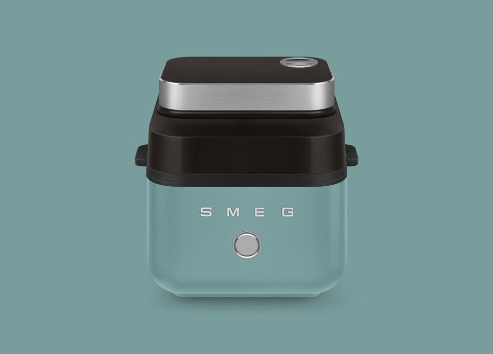 Friggitrice ad aria SMEG con finitura verde smeraldo opaca e dettagli cromati su sfondo a tinta unita.