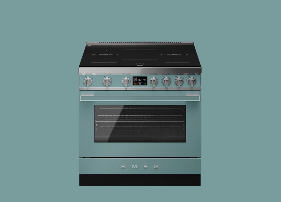Cucina a libera installazione SMEG da 90 cm in verde smeraldo opaco con piano cottura a induzione, manopole di controllo in acciaio inox e ampia porta del forno in vetro.