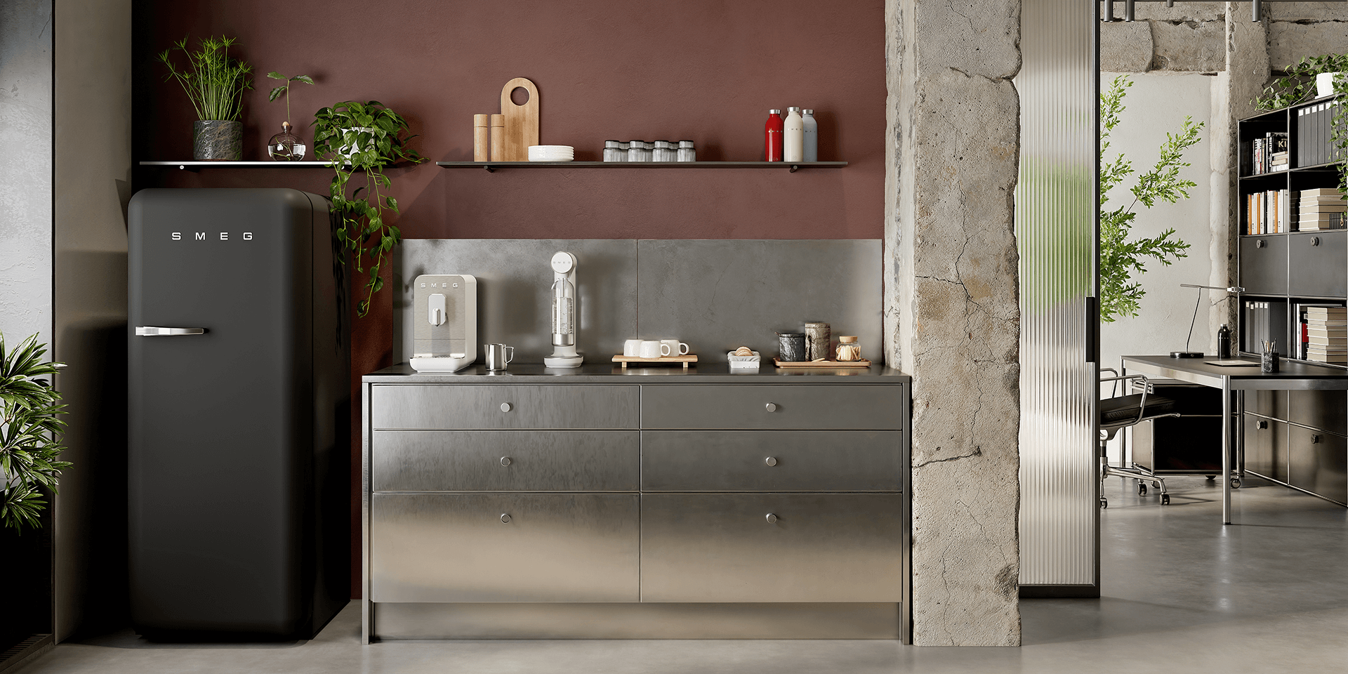 Modern kitchen interior featuring a matt black SMEG refrigerator alongside small countertop appliances in matte white finish, set against a warm brown wall with open shelves, plants, and a metallic cabinet base.