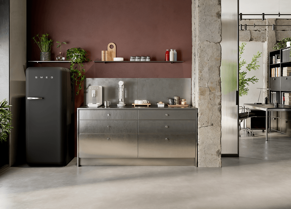 Intérieur de cuisine moderne avec des petits appareils électroménagers SMEG blancs mats posés sur un plan de travail en métal, à côté d'un réfrigérateur noir de style rétro, d'étagères ouvertes et de plantes décoratives