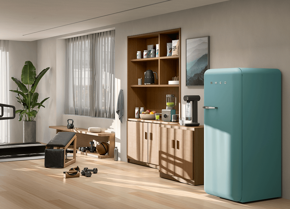 Coin cuisine compact équipé d'appareils électroménagers SMEG au fini vert émeraude, comprenant un réfrigérateur de style rétro, une machine à sodas et de petits appareils de comptoir, le tout mis en valeur par des meubles en bois aux teintes chaudes et des éléments bas bordeaux, avec un coin repas sur le côté.