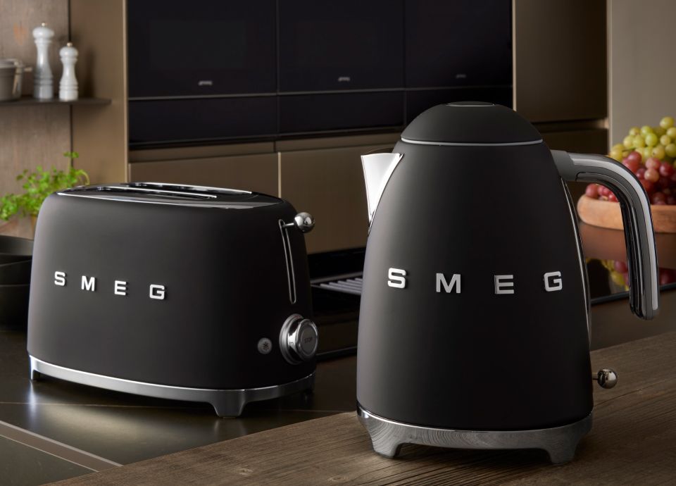 Close-up of a SMEG toaster and kettle in matte black set against a dark kitchen background