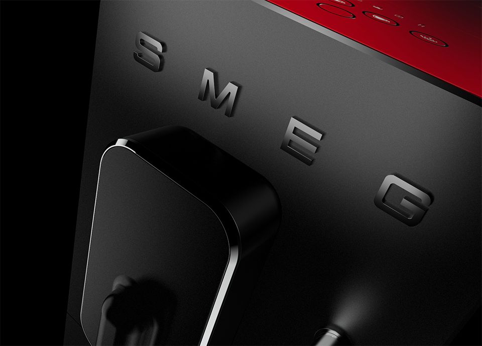 Detail of the front panel of the BCC12 917 Salzburg Porsche x SMEG Espresso Coffee Machine: the panel is black and features a chrome “SMEG” logo.