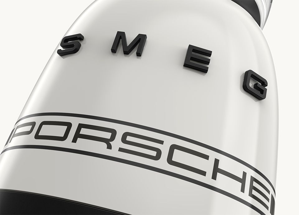 Detail van de blender in de kleur carrara wit. Op de voet staat de merknaam “SMEG” in grote hoofdletters en daaronder het woord “PORSCHE” in kleinere hoofdletters.