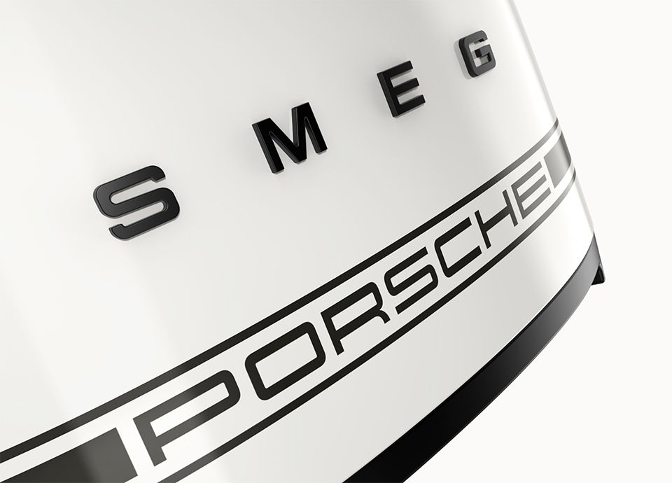 Detail van de voorzijde van de broodrooster in de kleur Carrara White. Op het front staat het merk “SMEG” in gedurfde hoofdletters, met daaronder het logo “PORSCHE” – een duidelijke verwijzing naar de samenwerking tussen beide merken.