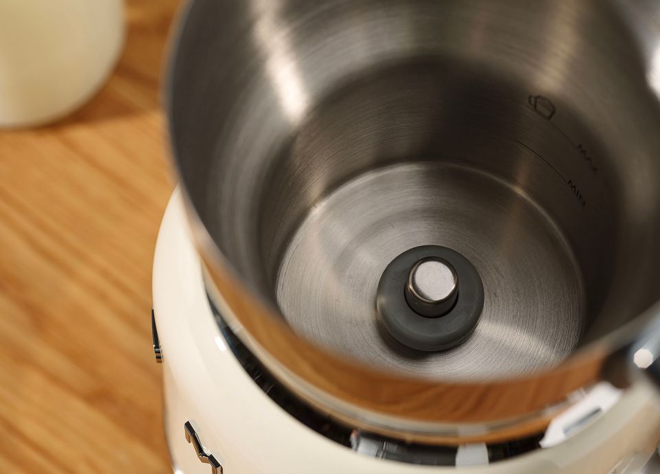 Close-up of a stainless steel milk frother jug interior showing the central connector for the whisk attachment.