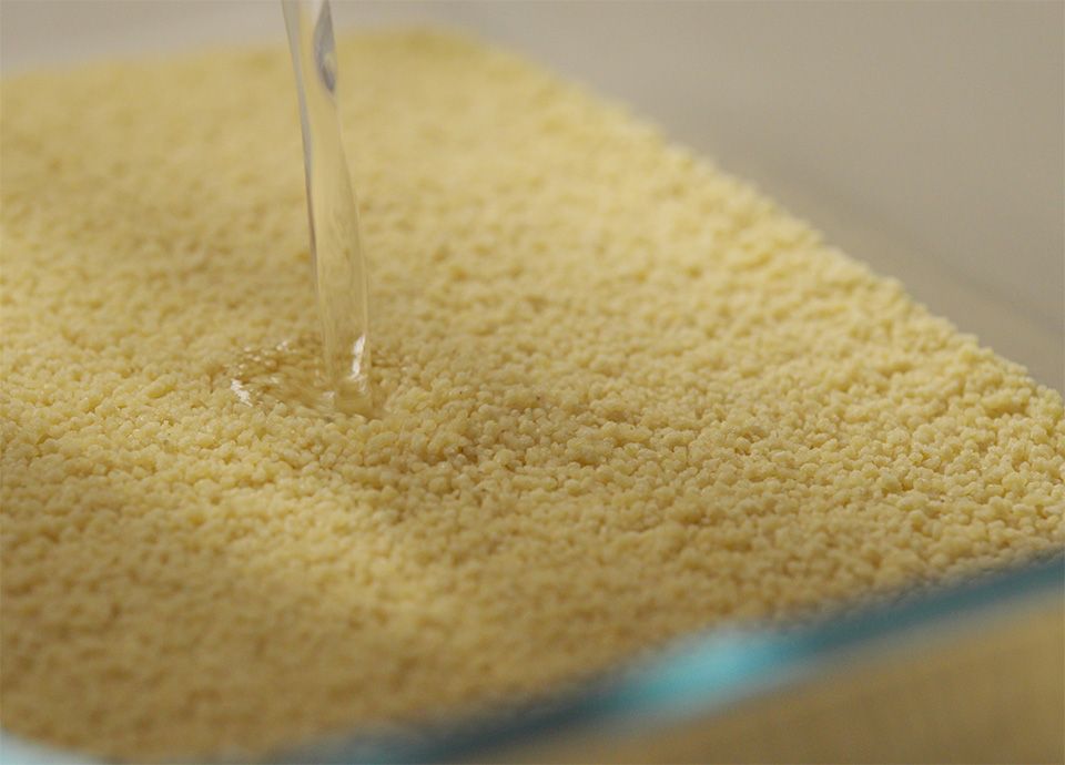 Hot water poured into couscous, ready to be cooked
