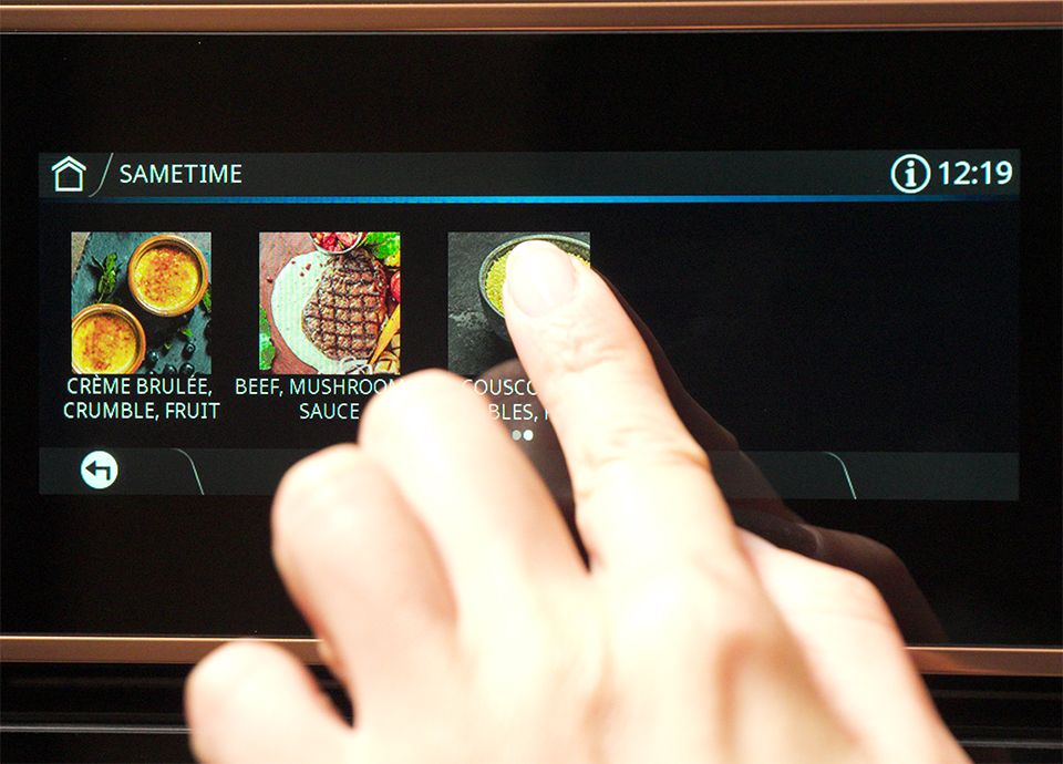 Hand adjusting the oven settings on the control panel