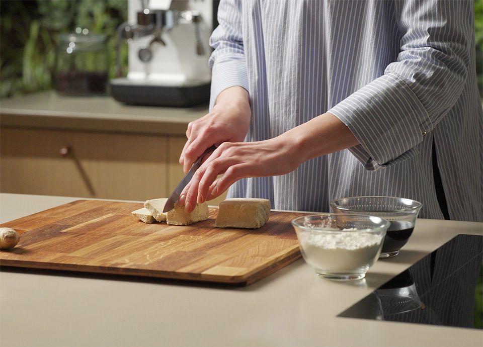 Person slicing tofu into pieces on a cutting board