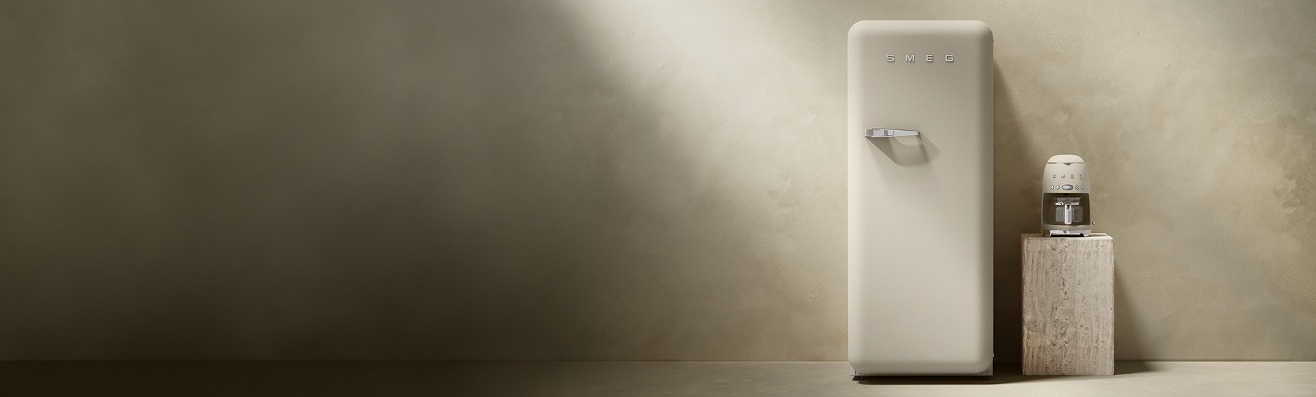 Moonlight SMEG refrigerator next to a matching drip filter coffee machine on a stone plinth, against a neutral textured background in a minimalist setting