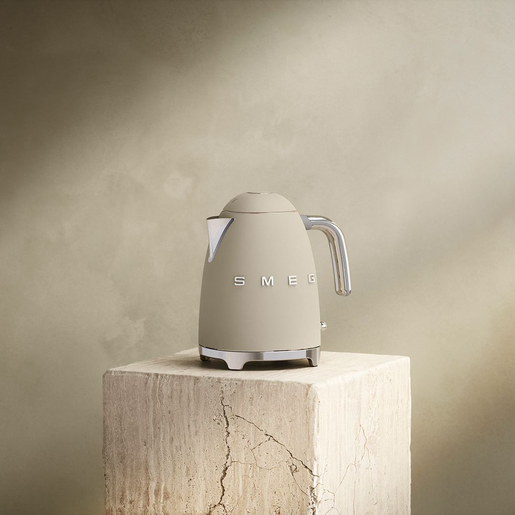 A Moonlight Smeg 50s Style kettle with chrome accents sits on a textured stone block against a neutral wall